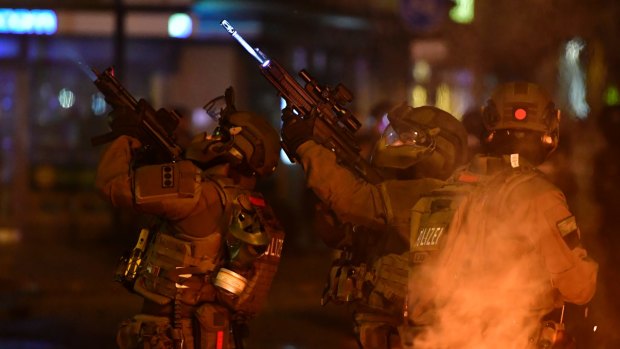 A SWAT team hold machine guns while observing an apartment during an anti-G20 protest.