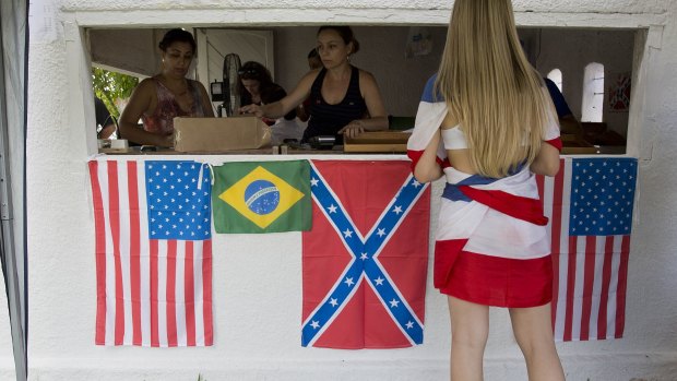 A woman buys beverages in a cashier decorated with American, Brazilian, and Confederate flags during a party to celebrate the 150th anniversary of the end of the American Civil War.
