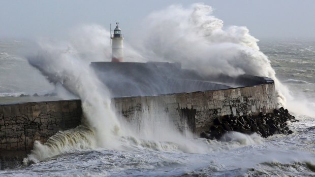 Waves crash over the lighthouse in Newhaven, East Sussex southern England.