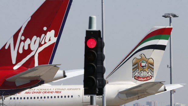 Virgin and Etihad planes are parked next to each other at Kingsford Smith airport in Sydney August 30, 2013. Virgin Australia Holdings Ltd reported a A$98.1 million ($87.6 million) full-year net loss on Friday, blaming difficult economic conditions, strong competition and one-off costs related to its recently acquired Skywest business. It also said major shareholders Air New Zealand, Etihad Airways and Singapore Airlines had agreed to provide a term loan worth A$90 million. The result contrasts with a well-received full-year net profit of A$6 million reported by rival Qantas Airways Ltd on Thursday. REUTERS/Daniel Munoz (AUSTRALIA - Tags: TRANSPORT BUSINESS)

AFR 14-11-2014