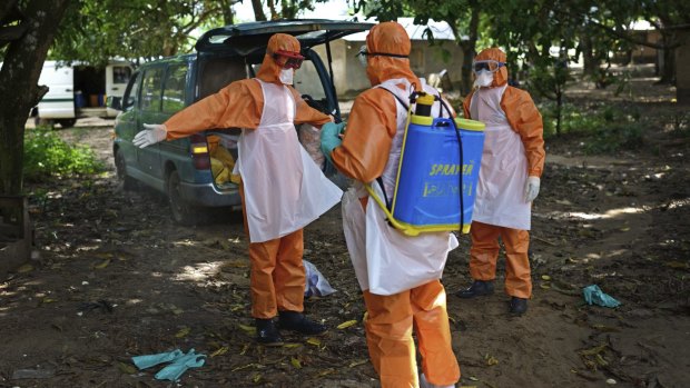 Members of a burial team spray themselves with chlorine after removing the body of a suspected Ebola victim in Sierra Leone last year.