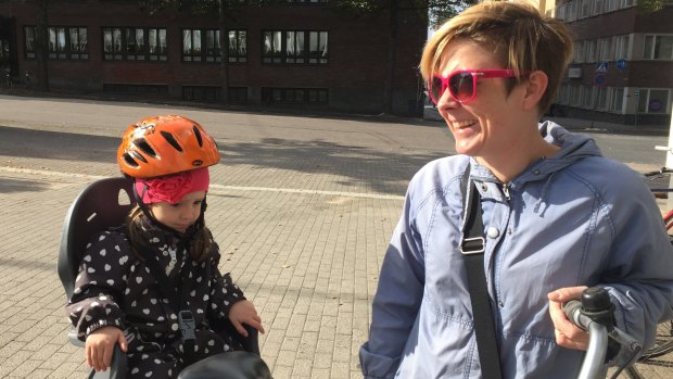 A Finnish mother is embarrassed that she hasn't got a bike helmet, but her daughter is wearing one. 