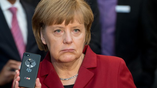 German Chancellor Angela Merkel holds a BlackBerry mobile device at a trade fair in 2013. A probe into the alleged tapping of her phone by US intelligence agencies has been dropped.