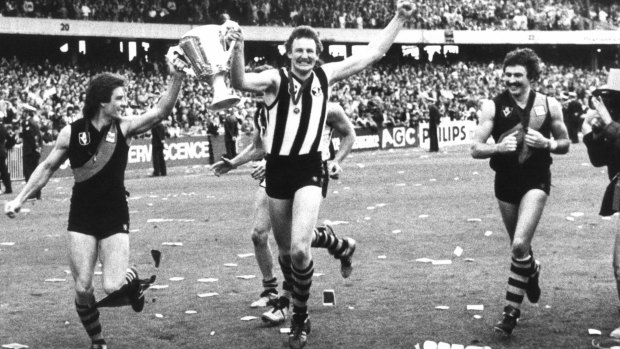 Richmond players after the club's grand final win in 1980. Geoff Raines and Michael Roach (in a Collingwood jumper after the end-of-game jumper swap) hold the premiership cup.