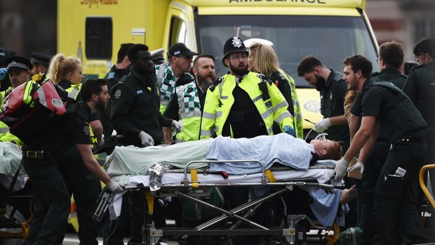 A member of the public is treated by emergency services near Westminster Bridge and the Houses of Parliament in London.