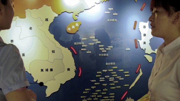 Workers chat near a map of South China Sea on display at a maritime defence educational facility in Nanjing in east China's Jiangsu province. 