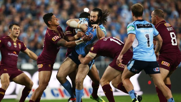 Tiger trapped: Blues prop Aaron Woods is tackled by the Queensland defence. 