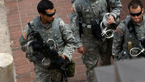 National Guard troopers carrying plastic handcuffs on the streets of Baltimore.