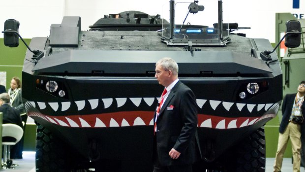 A businessman walks past an Iveco vehicle during the 2013 edition of the Defence & Security Equipment International arms fair  in London.