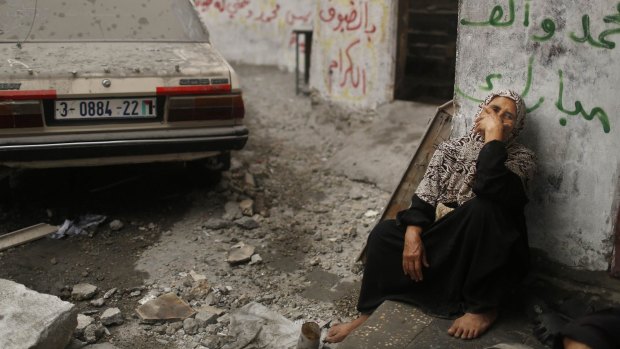 A Palestinian woman sits in a debris-strewn street in the northern Gaza Strip.