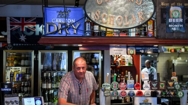 Mr Wulf behind the bar at his business, which he says is being hurt by the Metro rail tunnel construction works. 