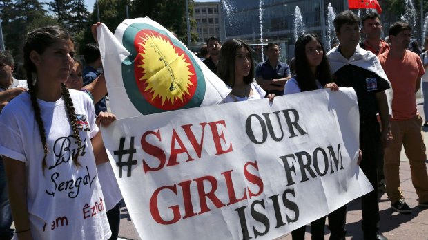 Women hold a banner at a demonstration on Monday at the UN European headquarters in Geneva, Switzerland, marking the first anniversary of Islamic State's surge on Yazidis of the town of Sinjar.