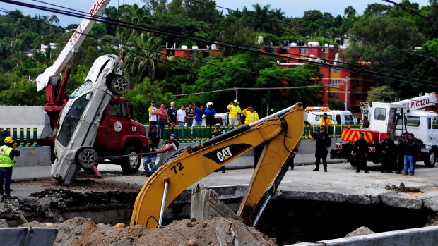 Rescue workers use a crane to lift a vehicle that drove into a sinkhole on a highway in Cuernavaca, Mexico.