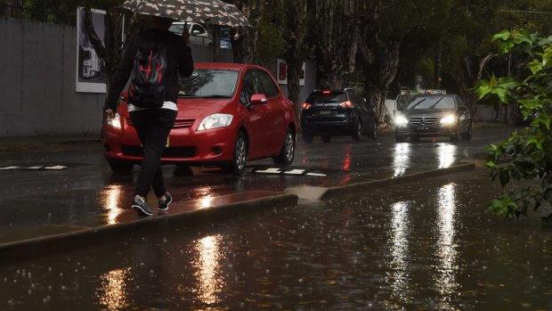 A pedestrian dodges flooding on Bourke Street in Alexandria.