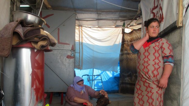 A Yazidi woman butchers a goat at the Khanke refugee camp. Young Yazidi girls have trained as photographers in order to help document their lives in exile.