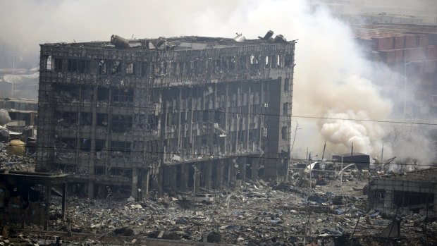 Smoke rises next to a damaged building at  the centre of the Tianjin blast.