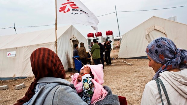 A mother carries her baby to the MSF medical clinic in Domiz refugee camp, Kurdistan, Iraq. Photographed in 2013.