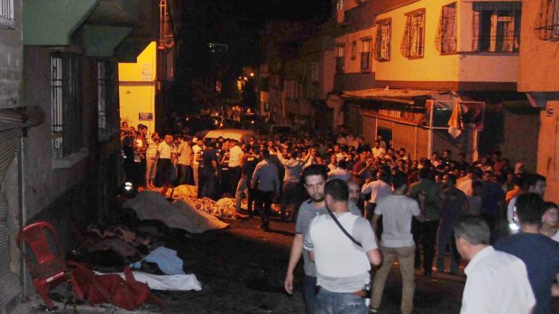 People gather after the explosion set off by a child suicide bomber, who either detonated the explosives or who was detonated from a distance, in Gaziantep, south-eastern Turkey.