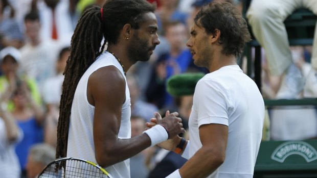 Dustin Brown shakes hands at the net with Rafael Nadal.