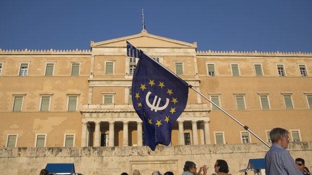 A protester holds a European Union flag with a euro currency symbol  at a rally outside the Greek parliament.