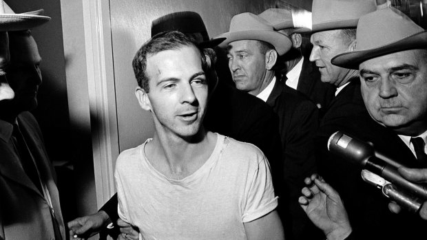 Surrounded by detectives, Lee Harvey Oswald talks to the media as he is led down a corridor of the Dallas police station.