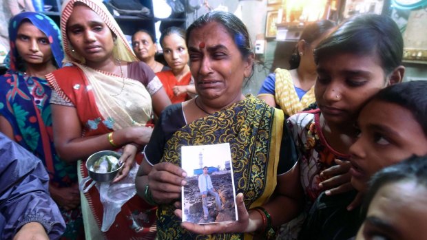 Grief stricken: An Indian family member holds a picture of a man killed when he drank the poisoned liquor.