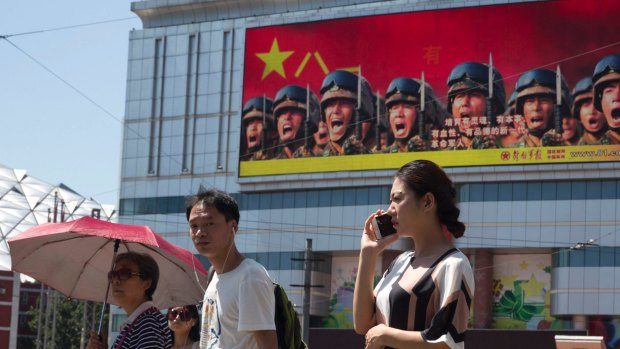 Beijing is intensifying its warnings to Indian troops to get out of a contested region. People wait at a traffic junction near a billboard advertising the Chinese military in Beijing.