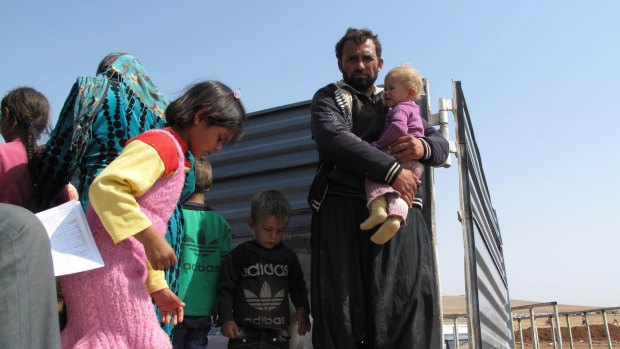 Ali Bourzan Isa holds his youngest daughter in the back of a truck that took them from the Turkish-Syrian border. 