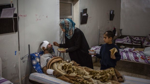 Kawther al-Obaid feeds her injured husband, Abdel Hemedi, as their son Bassam looked on at a hospital in Tal Abyad, Syria.