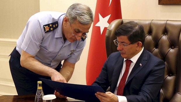 Turkish Prime Minister Ahmet Davutoglu (right) receives a briefing from the Air Force commander, General Akin Ozturk, during a security meeting in Ankara.