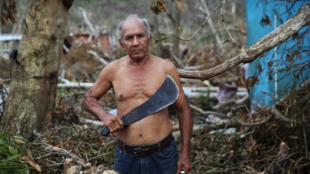 US Army veteran Luis Cabrera Sanchez holds his machete as he pauses for a portrait while clearing debris from his damaged hom in Yabucoa, Puerto Rico.