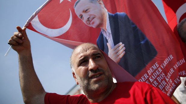 A Turkish man waves a flag, depicting the Turkish President Recep Tayyip Erdogan, during a rally in Istanbul on Sunday.