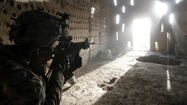 A US soldier points his rifle at a doorway after coming under fire by the Taliban in southern Kandahar province in 2012.