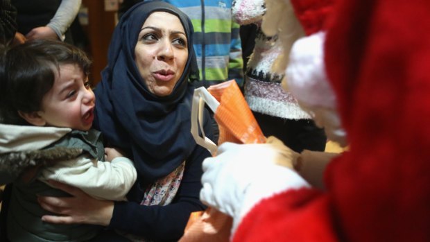 Syrian refugee Ola Hussain on Monday apologises to a volunteer dressed as Santa Claus as her son Mohamed cries at a migrant shelter in Berlin.