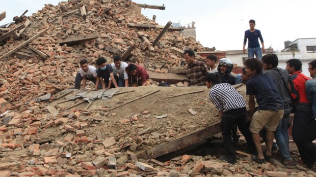 People try to lift the debris from a temple at Hanumandhoka Durbar Square after an earthquake in Kathmandu.
