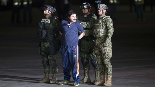 Joaquin "El Chapo" Guzman is made to face the press as he is escorted to a helicopter in handcuffs by Mexican soldiers and marines.