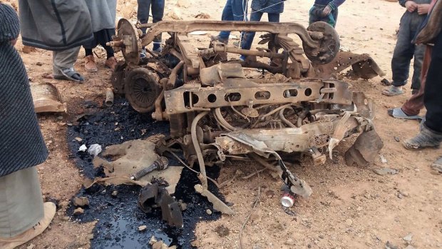 Civilians gather around the remains of a car bomb in the Rakban camp, near Syria's border with Jordan.