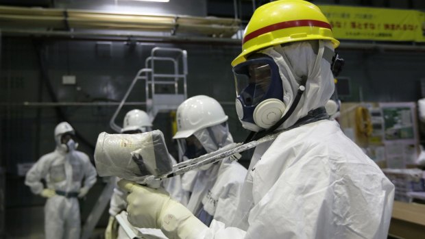 An official of Tokyo Electric Power Co measures radiation past a pool of spent nuclear fuel at the  reactor in 2013.
