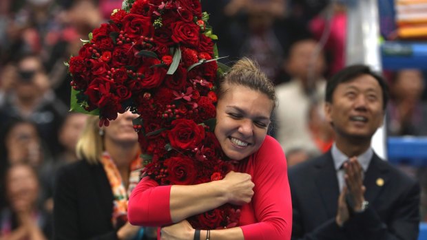 On top of the world: Simona Halep of Romania hugs a floral bouquet in the shape of the number one after beating Jelena Ostapenko.