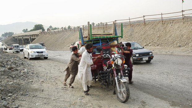 Just off the Pul-e-Saracha bridge, Hayatullah and family members push all the possessions they could take on their three-wheeled vehicle that had broken down. 