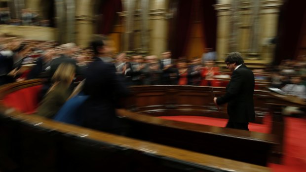 Catalan regional President Carles Puigdemont is applauded after delivering his opening speech at the parliament in Barcelona.