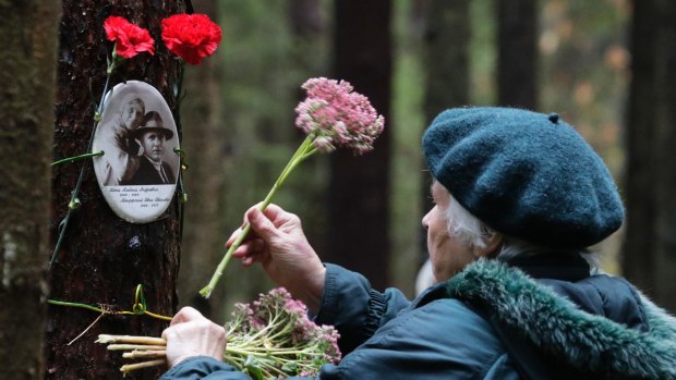 A woman places flowers at a memorial in Levashovo Cemetery that is the resting place of victims of Stalin's Great Terror.