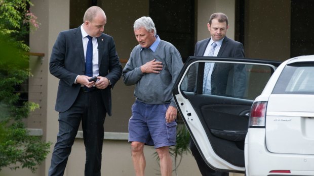Bill Spedding, centre, is arrested in his Bonny Hills home by detectives on Wednesday.  