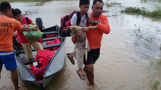 A boy and his dog are carried to higher ground in Isabela province, northern Philippines, on Monday.