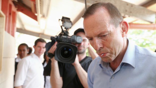 Prime Minister Tony Abbott, nail in his mouth, gets to work helping to build a cubby house during his visit to Bamaga Senior School, Cape York, on Wednesday.