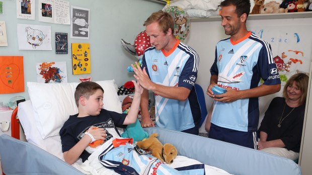 Easing the blues: Rhyan Grant and Alex Brosque present hospitalised fan Zachary Chidiac with a team shirt.