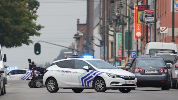 A police vehicle blocks a road in front of an explosives robot.