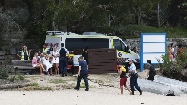 Onlookers wait with police at Shelly Beach, where a diver was pulled from the water.