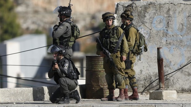 Israeli security troops take positions at the scene of a stabbing attempt in Hebron on Sunday.
