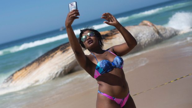 A woman poses for a selfie in front of the carcass of a humpback whale on Ipanema beach, in Rio de Janeiro.